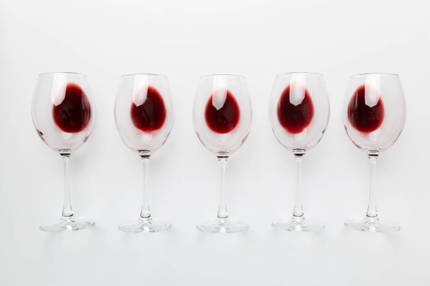 Viele Gläser Rotwein bei der Weinprobe. Konzept des Rotweins auf farbigem Hintergrund. Draufsicht, flache Verlegung. - Foto, Bild
