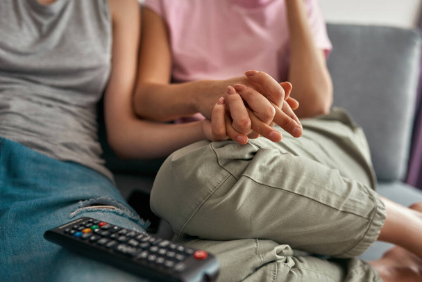 Lesbian girls hold hands during watch TV at home - Valokuva, kuva