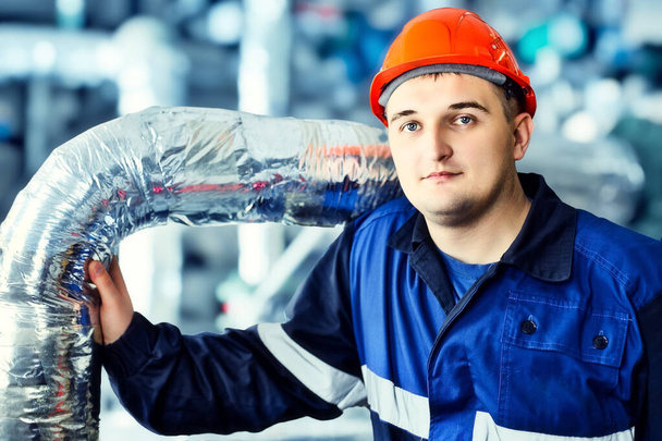 Retrato de jovem engenheiro no capacete em ambiente de trabalho na fábrica. Trabalhador a gás confiantemente olha diretamente para a câmera - Foto, Imagem