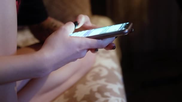 Bir kız karanlık bir odada bir kanepede oturuyor, elinde bir telefon tutuyor ve hızlıca bir mesaj yazıyor. Sohbet.. - Video, Çekim