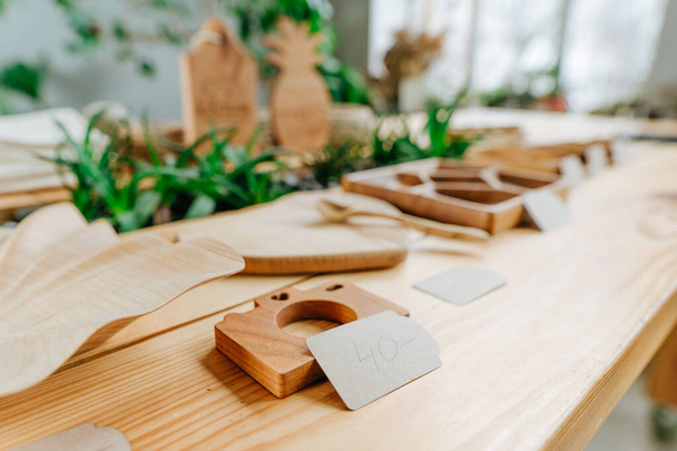Wooden photo camera toy and other wooden products with price tags on the table at shop. Selective focus. - 写真・画像