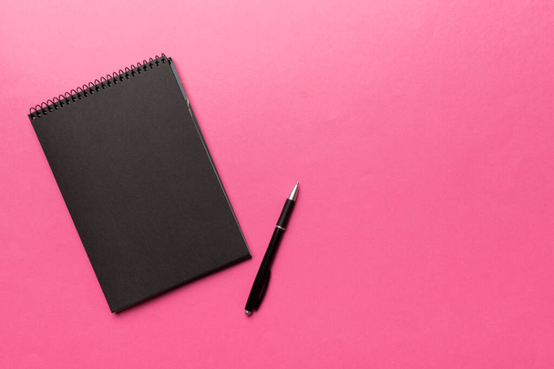 school notebook op een gekleurde achtergrond, spiraalvormige zwarte notitieblok op een tafel. - Foto, afbeelding
