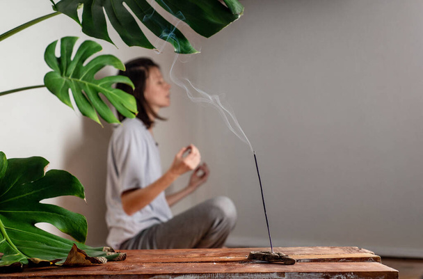 White Female meditates in a room with a stick of incense smoking. The concept of spiritual practice and mental health. Copy space - Fotó, kép