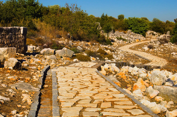 Scenic ancient winding cobble stone pathway along the ruins of antique buildings. Kanlidivane ancient city in Mersin Province, Turkey. Travel and tourism concept. - Foto, immagini