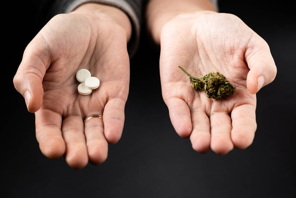 Marijuana and pills on female palms. Medical cannabis as an alternative to drugs concept. - Zdjęcie, obraz