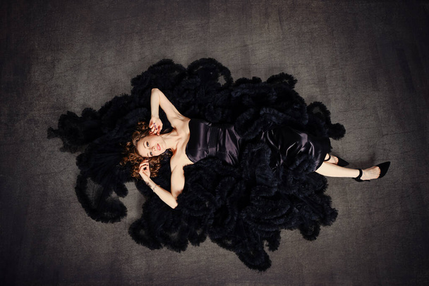 Fashion model in a luxurious puffy black dress lying on a floor - Zdjęcie, obraz