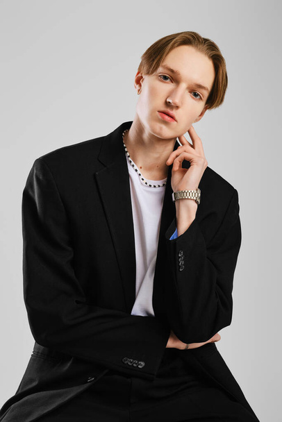 Studio shot of young thoughtful man in a black suit - Foto, Bild