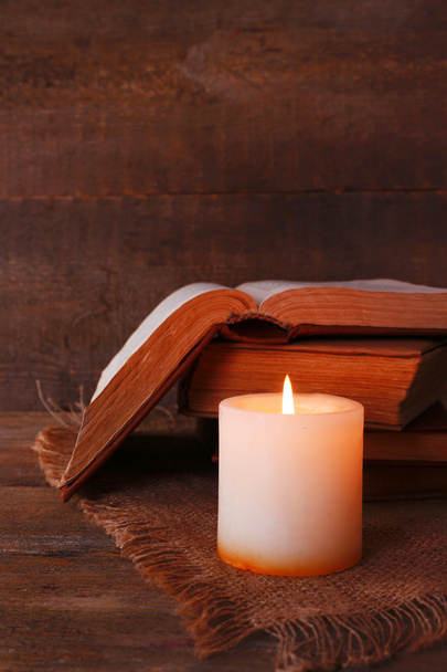 Books and candle on napkin on wooden table on wooden wall background - Fotografie, Obrázek
