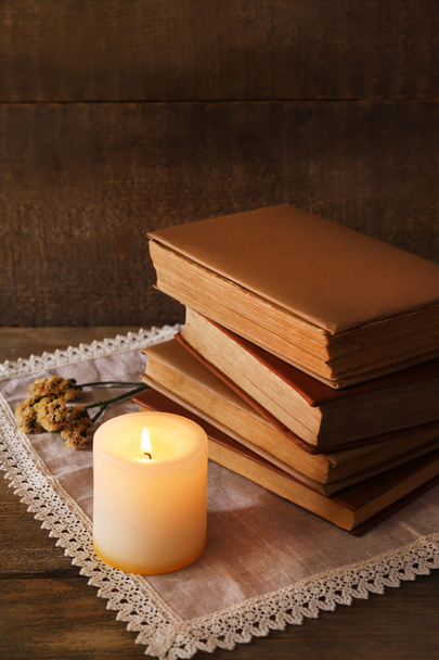 Books, flowers and candle on napkin on wooden table on wooden wall background - Photo, Image