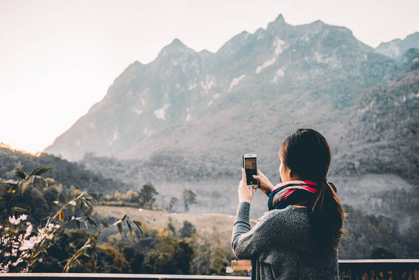 美しい山の景色の彼女の電話で写真を撮る若い女性 - 写真・画像