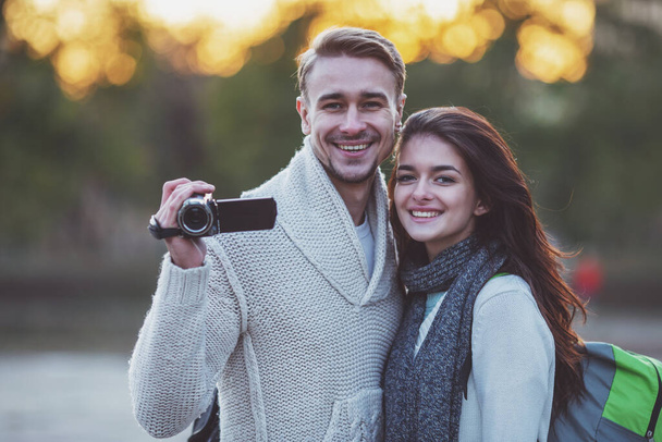 Jeune beau couple de touristes utilisent la caméra lors d'une promenade dans la ville
 - Photo, image