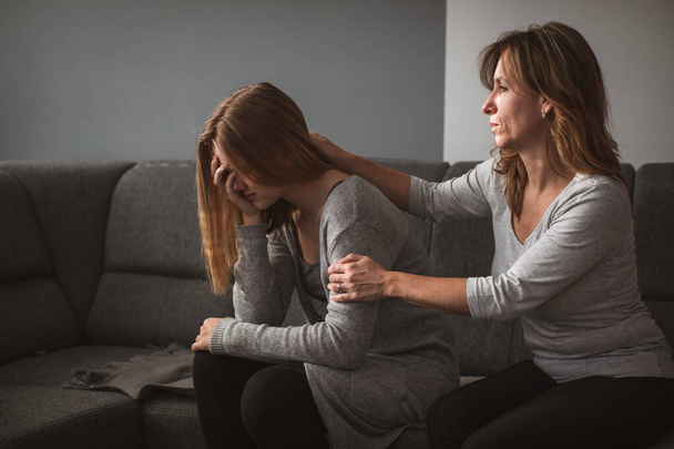 Depressed teen suffering from anxiety being taken care of by her caring mother - Foto, Bild
