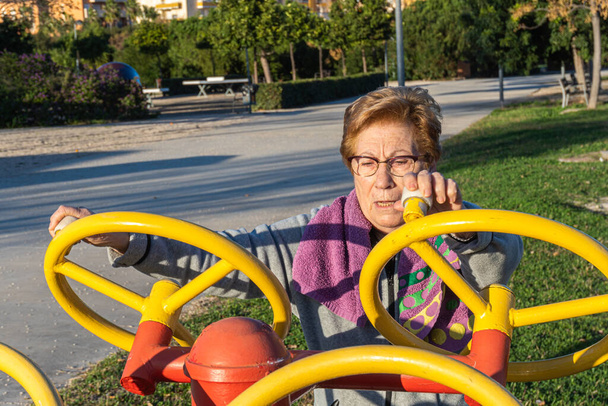 Seniorin bewegt Spinnräder in einem biologisch gesunden Park bei Sonnenuntergang - Foto, Bild