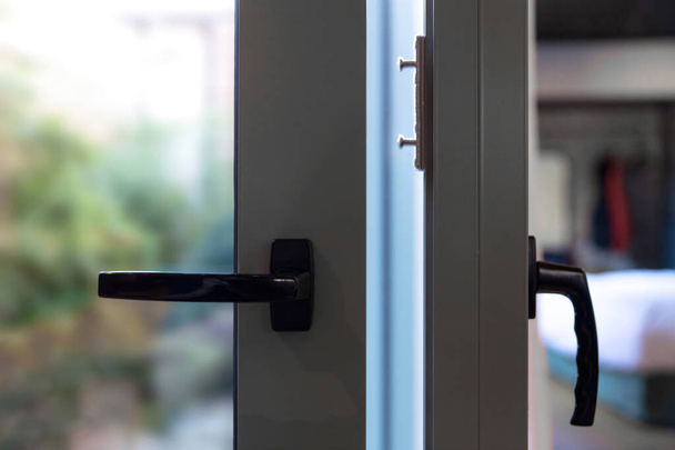 Metal door frame, aluminum glass window and handle detail. Two sliding doors open and closed closeup view, blur outdoor background - Photo, Image