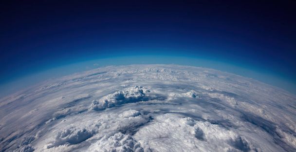 Planet Erdkrümmung. Luftaufnahme. Blauer Himmel über dichten Wolken. Raumfahrt-, Wissenschafts- und Wetterkonzept - Foto, Bild