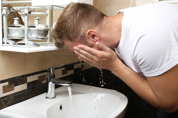 Young man shaving his beard in bathroom - Фото, зображення