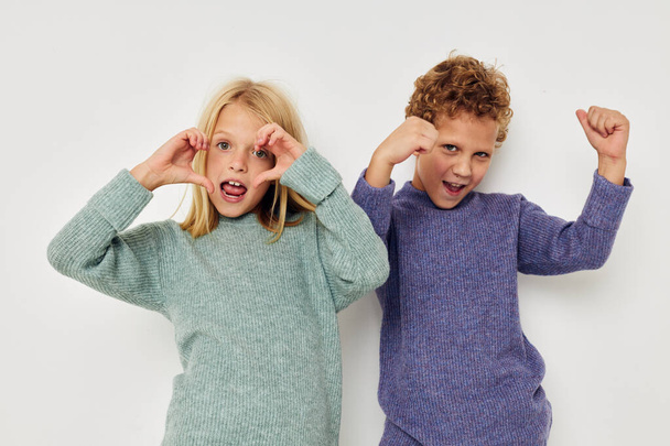 Boy and girl in multi-colored sweaters posing for fun Lifestyle unaltered - Foto, afbeelding