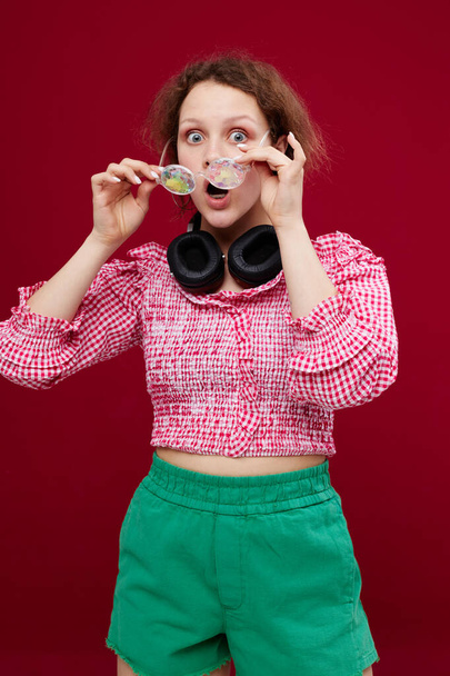 portrait of a girl in green shorts glasses with diamond headphones posing - Фото, зображення