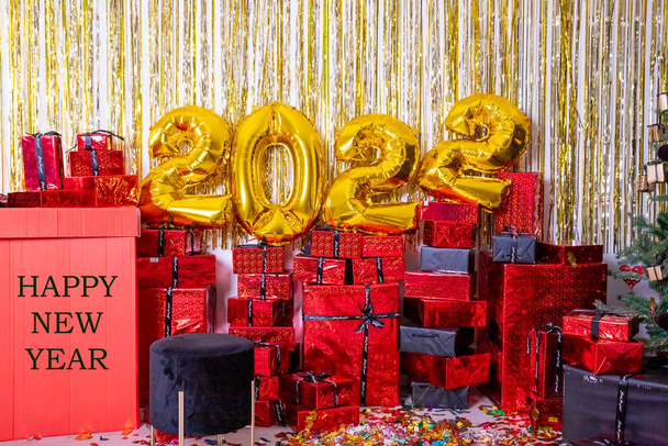 2022 inflatable golden balloons and glittering decorations. New Years concept.Balloons made of gold foil with presents and confetti. Party decoration. Text happy new year - Foto, Bild