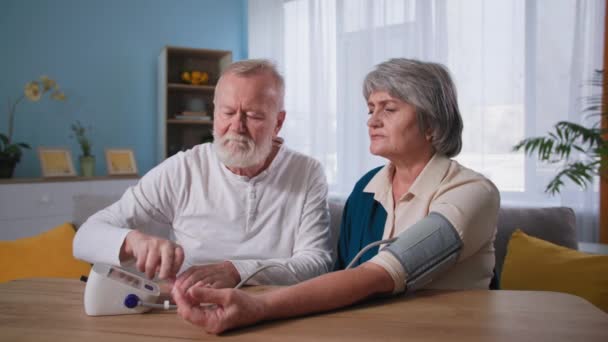 kardiológia, idős pár vérnyomásmérés, idős férj és feleség magas vérnyomással - Felvétel, videó