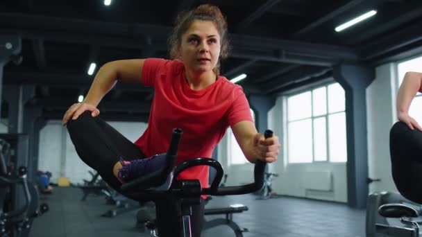 Groep van lachende vrienden vrouwen klasse oefenen, trainen, stretching op stationaire fiets in de sportschool - Video