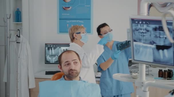 X線スキャンを分析して診断を見つける上級歯科医と看護師 - 映像、動画