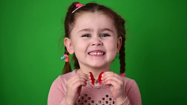 Petite fille sourit et tient une plaque dentaire. - Séquence, vidéo
