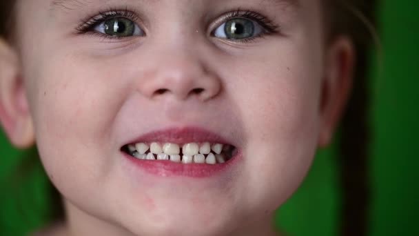 La niña muestra sus dientes de leche, dientes de leche blancos, higiene bucal, movimiento lento del niño. - Imágenes, Vídeo
