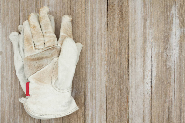 Бруд покритий шкіряними робочими рукавичками на вивітреному дереві для вашого будівництва або повідомлення про роботу на подвір'ї
 - Фото, зображення
