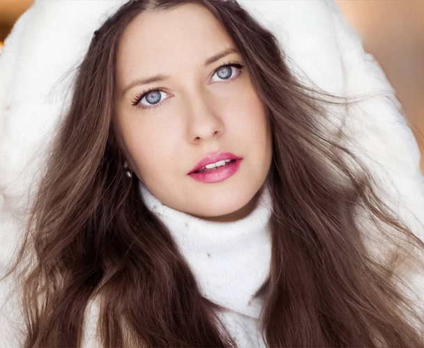 Winter fashion and Christmas holiday look. Beautiful woman wearing white sweater and fluffy fur coat with hood wrap, glamour makeup and hairstyle as xmas portrait - Zdjęcie, obraz
