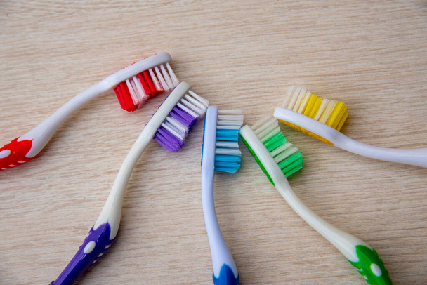 Colored toothbrushes on the wooden background - 写真・画像