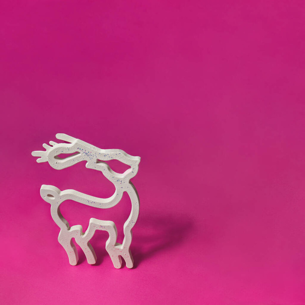White reindeer silhouette on pink background. Minimalistic Christmas and New Year holidays concept. Creative Xmas greeting card composition. - Fotó, kép