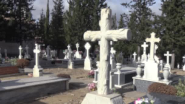 Rozmazaný rozostřený pohled na náhrobky na hřbitově s náhrobkem, starým bílým křížem a cypřišem ve Španělsku. Španělský venkovský hřbitov. - Záběry, video