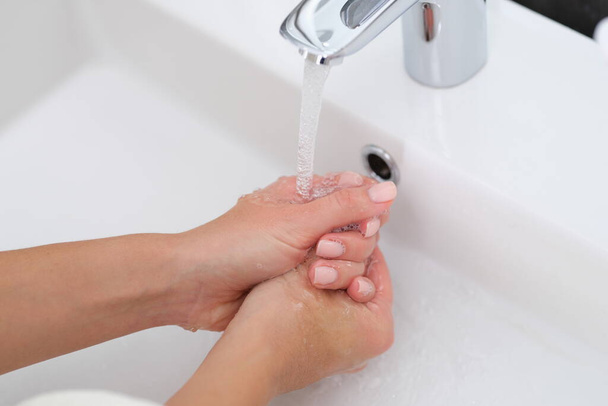 Una mujer se lava las manos bajo el grifo - Foto, imagen