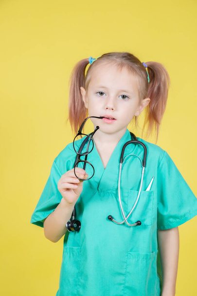 Portrait of serious little caucasian kid dressed in doctors green coat - Foto, imagen