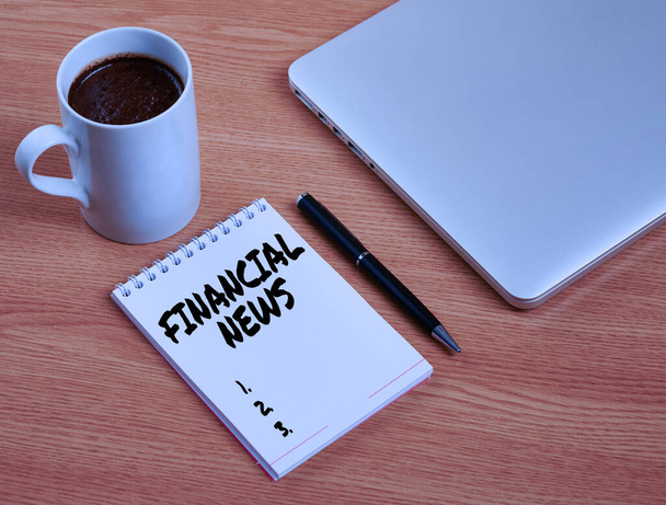 Conceptual display Financial News. Word for Investment banking Fund management Regulation and trading Closed Laptop Beside Empty Journal With Pen And Coffee Mug Over Table. - Foto, Bild
