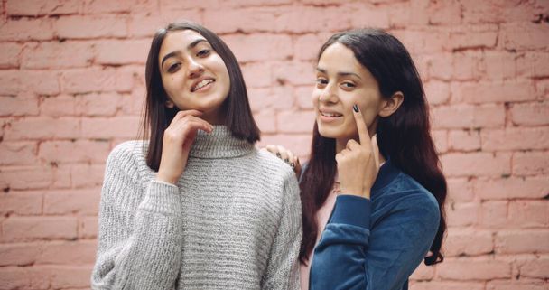 two young women in casual clothes on a brick wall background. - Foto, afbeelding