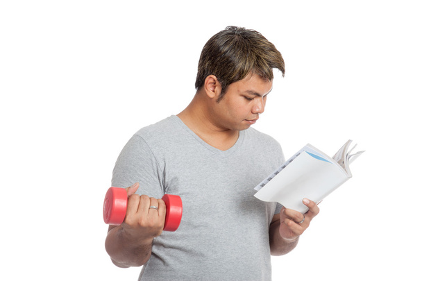 Asian man reading a book with red dumbbell - Zdjęcie, obraz