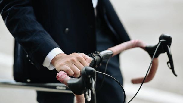 Hombre de negocios de tiro recortado con bicicleta caminando por la calle de la ciudad durante un viaje matutino. - Foto, Imagen