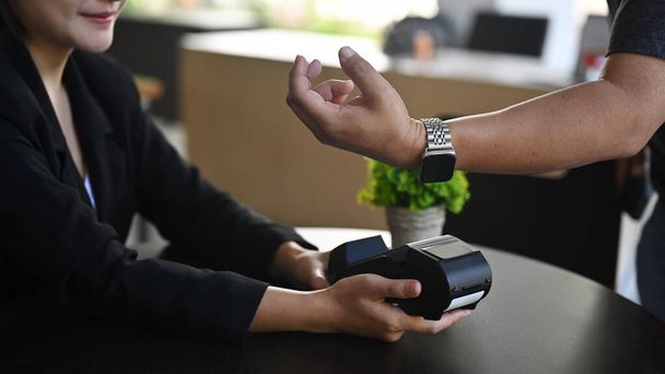 Обрізаний постріл людина клієнт використовує термінал для безконтактних платежів зі смарт-годинником в кав'ярні
. - Фото, зображення