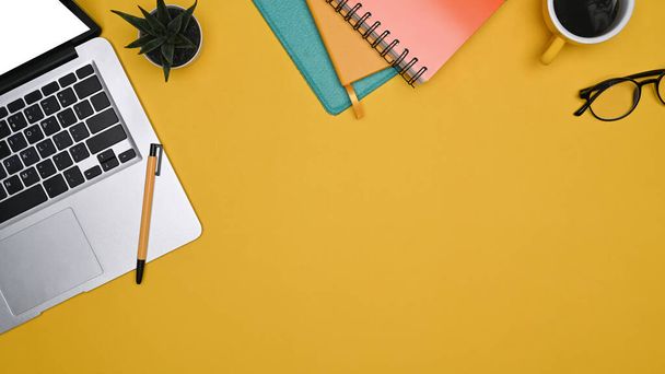 Computer-Laptop, Notizbuch und Kaffeetasse auf gelbem Hintergrund. - Foto, Bild