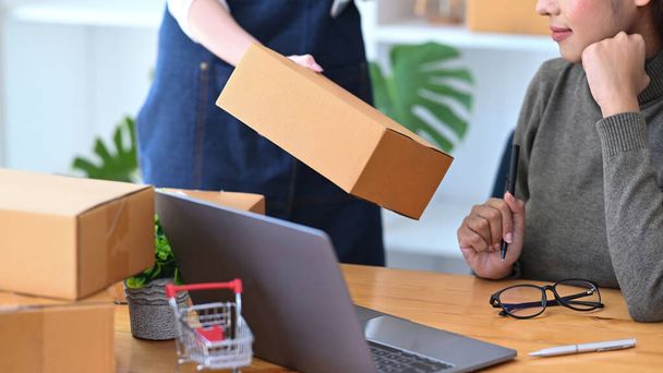 Dos mujeres jóvenes ponen en marcha dueño de una pequeña empresa que prepara la caja del paquete del producto para entregar al cliente. - Foto, imagen