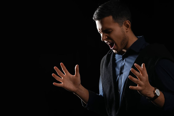 Portrait of screaming young man on black background - Photo, image