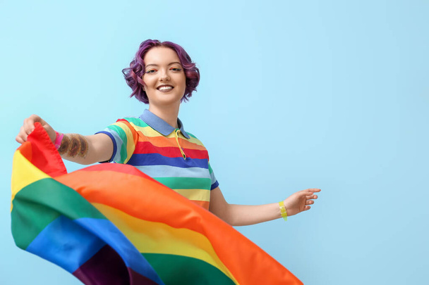 Junge Frau mit LGBT-Flagge auf blauem Hintergrund - Foto, Bild