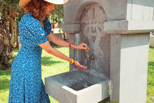 Женщина моет руки в источнике уличной воды. Гигиена во время пандемии коронавируса и других инфекций - Фото, изображение