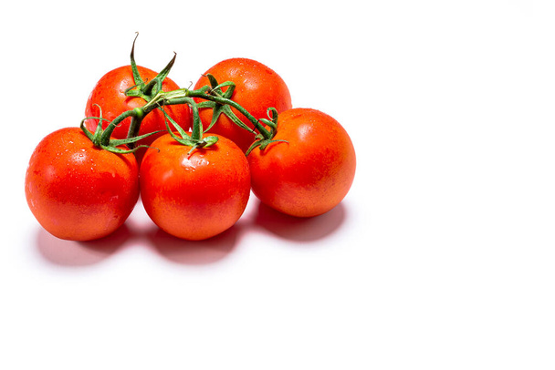 Foto de un ramo de cinco tomates naturales rojos húmedos sobre un fondo blanco.La foto tiene espacio para copiar. - Foto, Imagen
