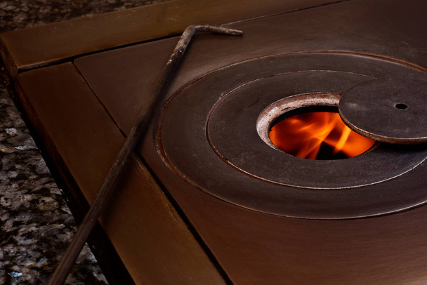 Photographie d'un feu dans un poêle à charbon de bois. La photo a un style vintage et est prise dans un format horizontal. - Photo, image