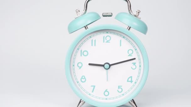 El despertador azul muestra el correr del tiempo. El movimiento de las manecillas del reloj pasó rápidamente. Sobre el fondo blanco. - Metraje, vídeo