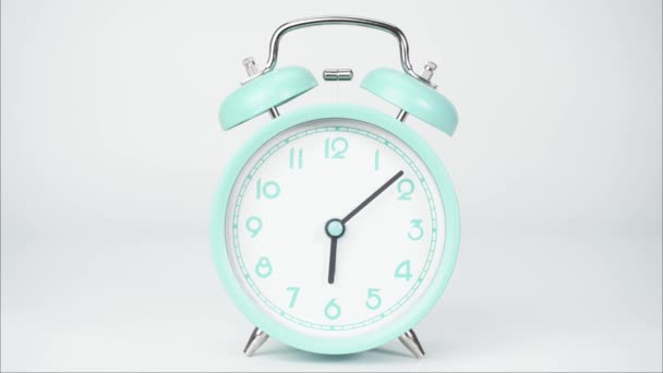 El despertador azul muestra el correr del tiempo. El movimiento de las manecillas del reloj pasó rápidamente. Sobre el fondo blanco. - Metraje, vídeo