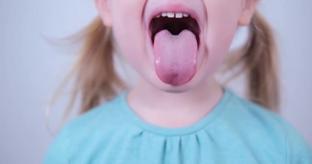 La ragazzina bionda mostra lingua, gola. Addestramento infantile della logopedia muscolare. - Filmati, video